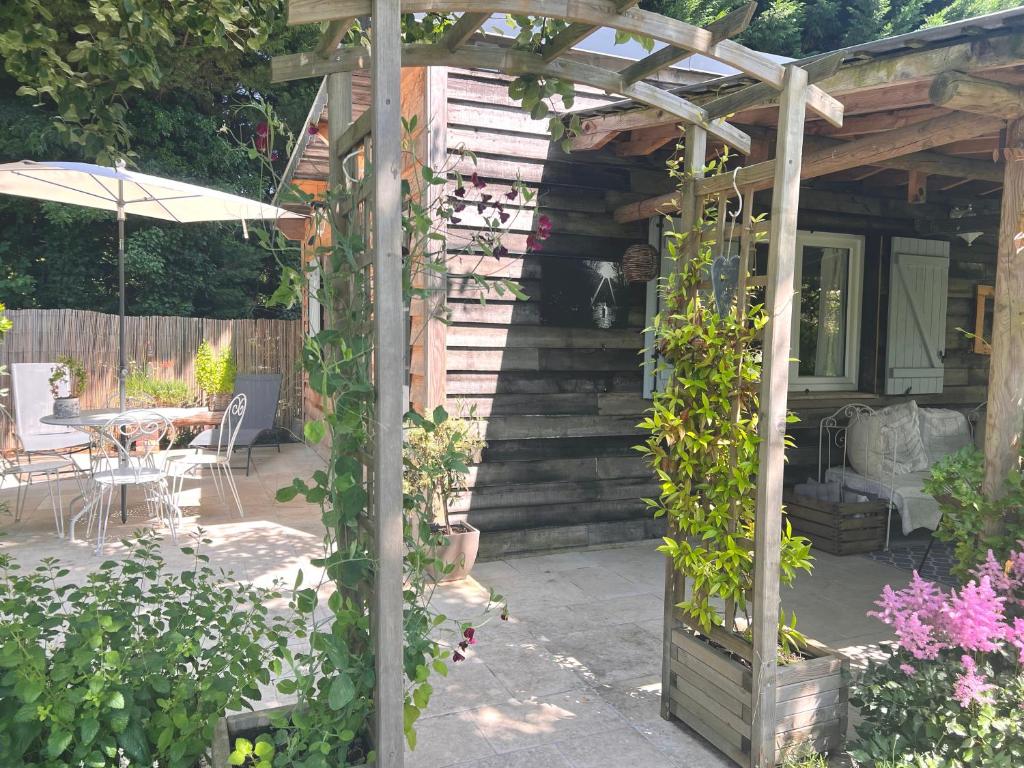 un jardin avec une pergola, une table et des chaises dans l'établissement La Maison de Manou, à La Noë-Poulain