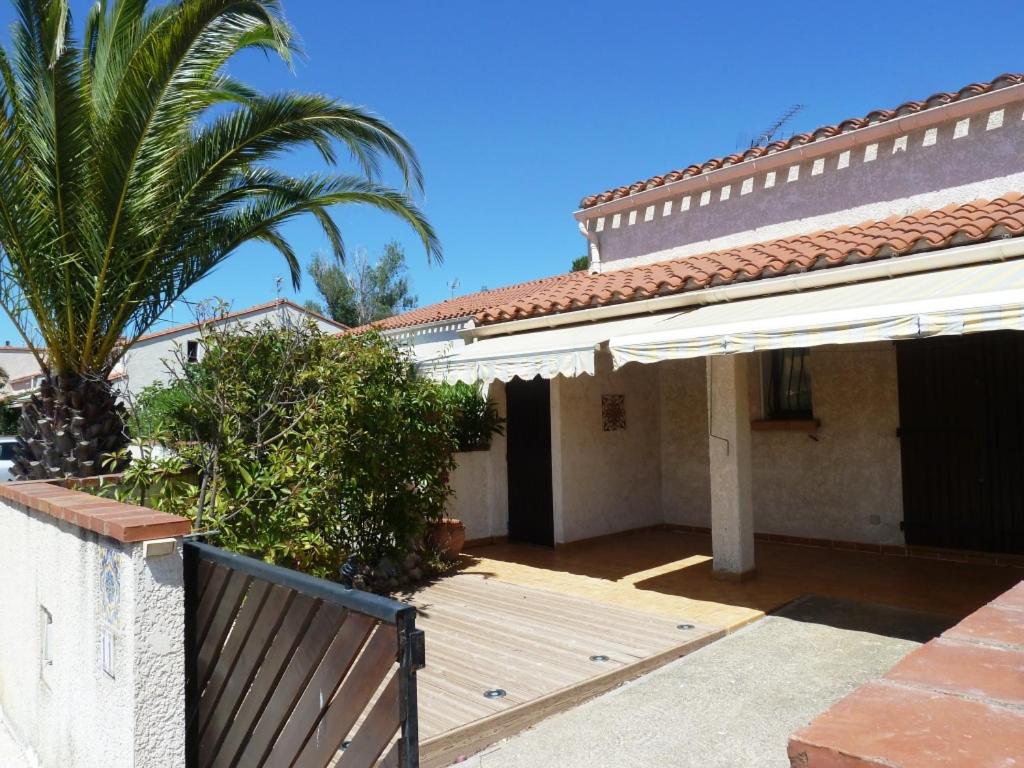une maison avec un porche en bois et un palmier dans l'établissement Villa calme climatisée idéalement située Mer Port Centre, à Saint Cyprien Plage