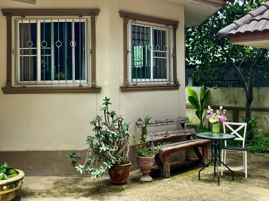 a house with a bench and a table and some plants at Yoga Bed and Breakfast in Chiang Mai