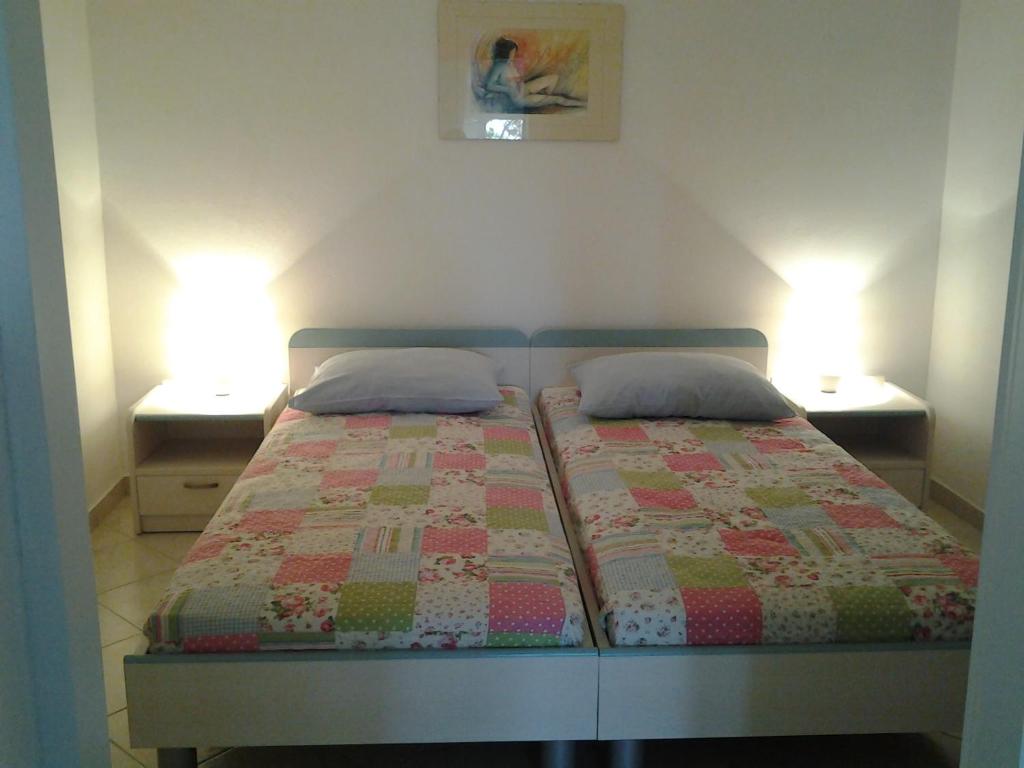 a bedroom with a bed with two nightstands and two lamps at Apartments MiaMaja in Novalja