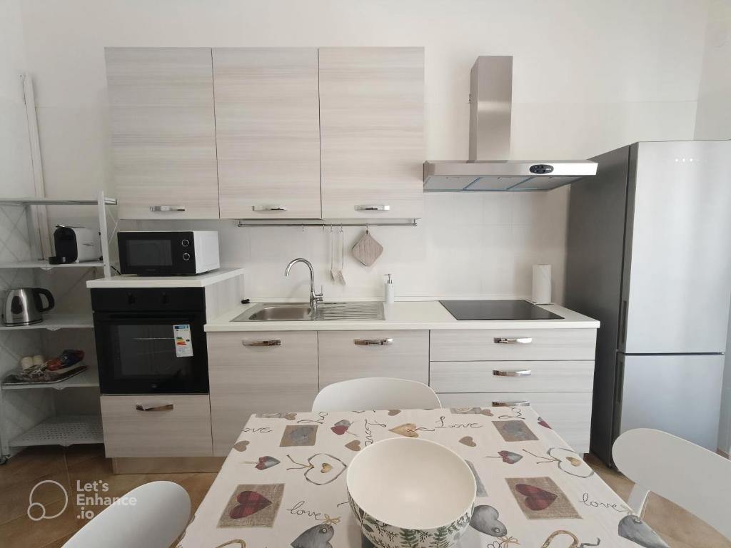 a kitchen with white cabinets and a table with chairs at Marinella House in Siracusa