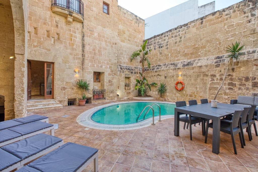 a patio with a table and a swimming pool at New to the market - Unique house with pool by SF Homes in Għargħur