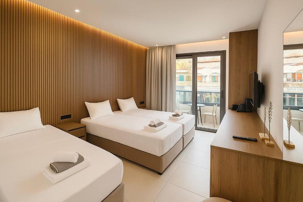 a hotel room with two beds and a television at NÓA Rooms - Adults Only in Ayia Napa