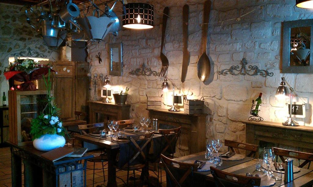 un restaurante con mesas y sillas de madera y una pared de piedra. en L' Oustaloun, en Maussane-les-Alpilles