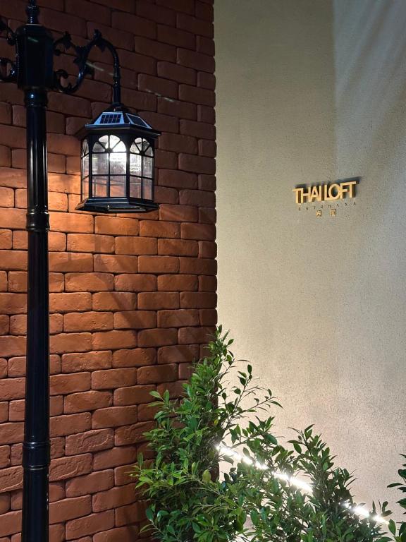 a light next to a brick wall with a sign at Thai Loft 泰閣 in Bangkok