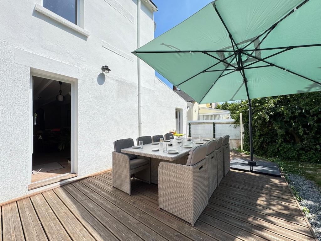 a table with chairs and an umbrella on a deck at La Gambade - Wifi, Jardin, BBQ, 1500 m de la mer in Mesquer