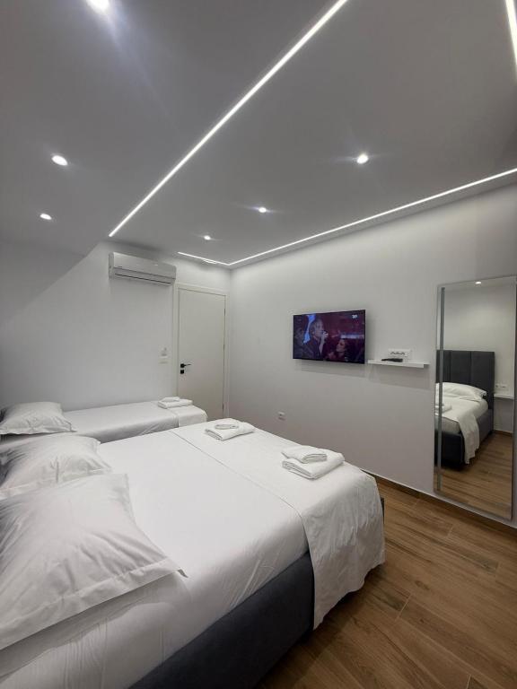 a white bedroom with a large bed and a mirror at Hotel Barjami in Sarandë