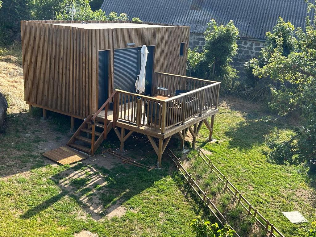 une petite maison avec une terrasse et un parasol dans l'établissement Lou Mazet Séjour en Aubrac, à Saint-Laurent-de-Muret