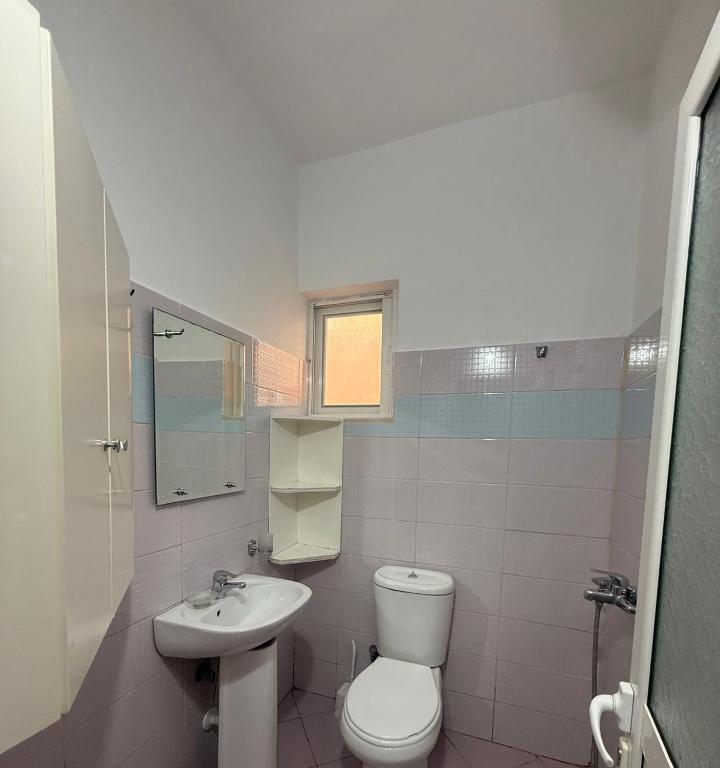 a white bathroom with a toilet and a sink at Hotel Barjami in Sarandë