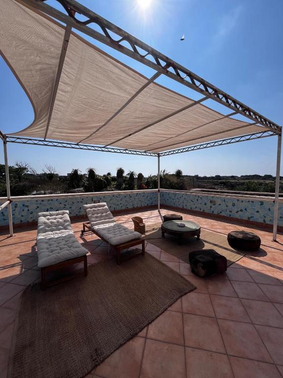 a patio with chairs and a white canopy at Suite Casa Paola in Casa De Giorgis