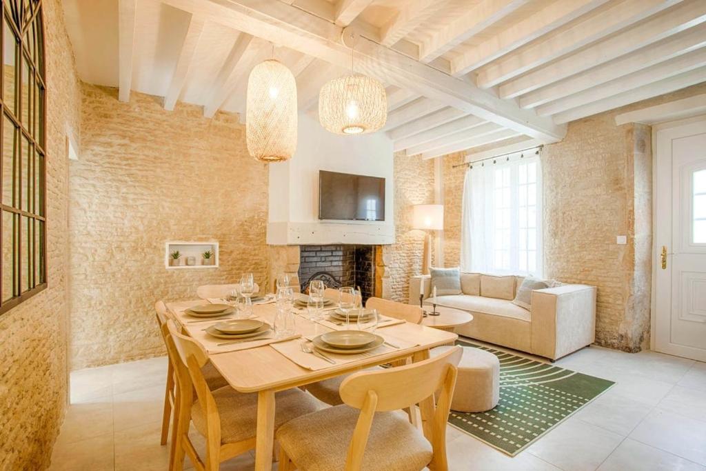 Maison Spa et Sauna, Cœur de la Normandie في Ranville: مطبخ وغرفة معيشة مع طاولة وكراسي