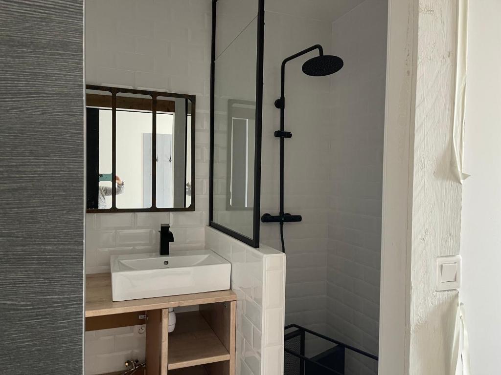 a white bathroom with a sink and a mirror at Les sereins 