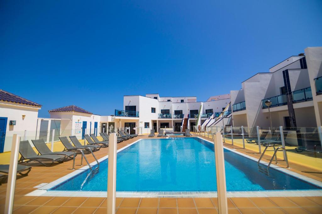 a swimming pool with chairs and a building at TAO El Cotillo in El Cotillo