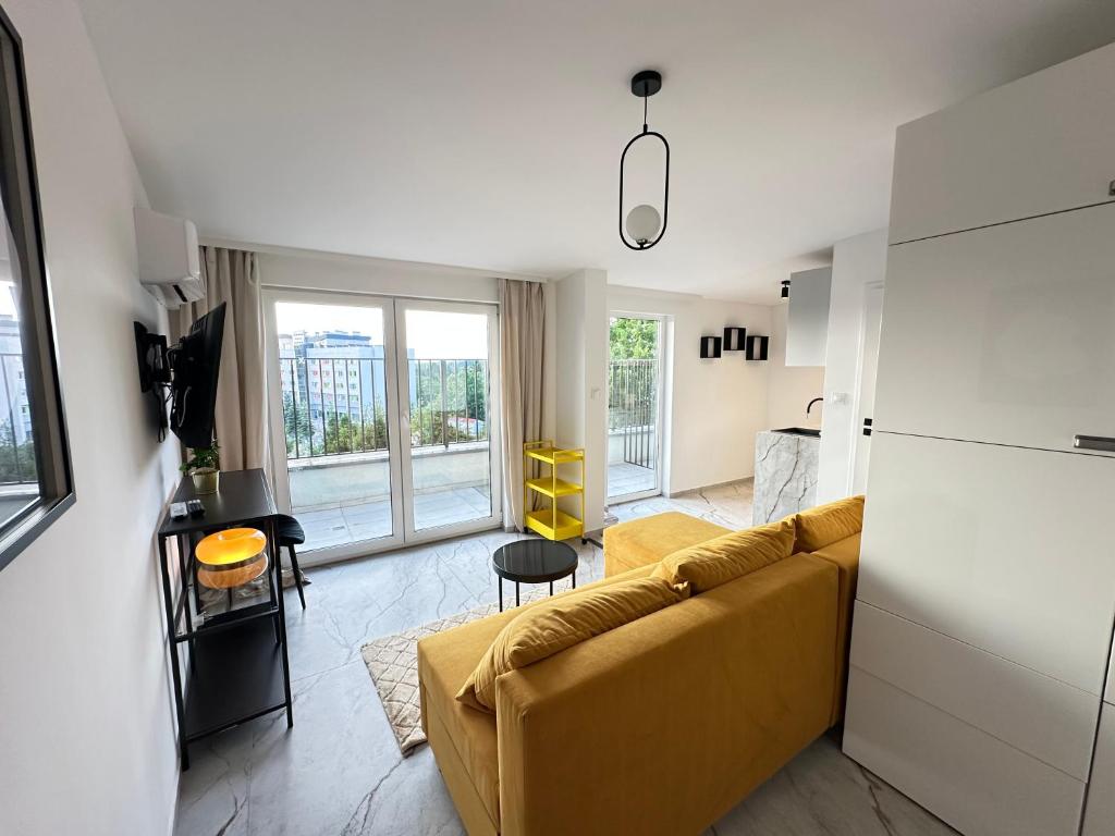Una sala de estar con un sofá amarillo y una cocina. en MOVEEN! Apartamenty Wrocław Nowoczesne studia z parkingiem! 10 min od centrum, en Wroclaw