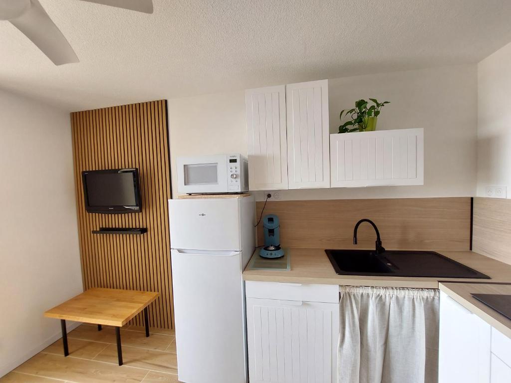 una cucina con frigorifero bianco e forno a microonde di Appart avec loggia en front de mer et superbe vue a Le Barcarès