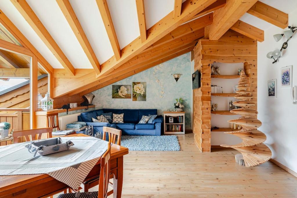 a living room with a blue couch and wooden ceilings at Mansarda sul Lago di Molveno in Molveno