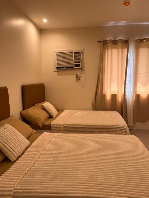 a hotel room with two beds and a window at BRP Luxe Condo with Parking and Wifi in Davao City