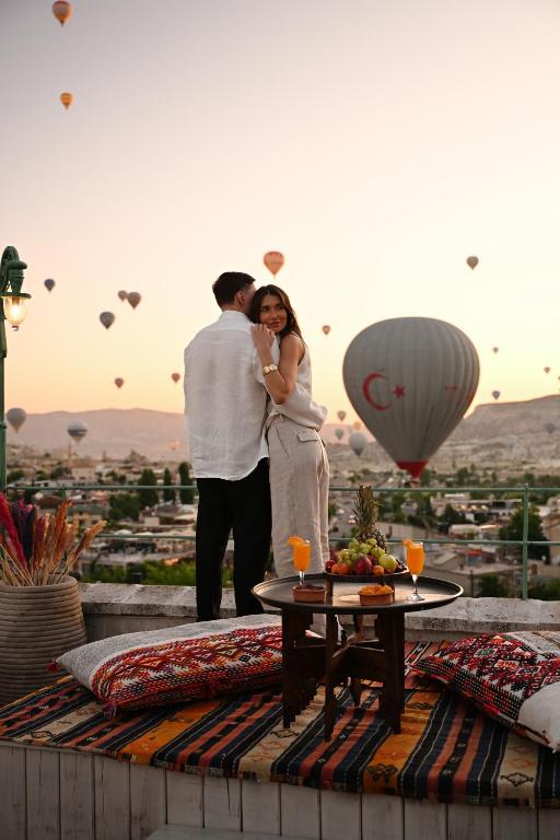 a man and a woman standing on a rooftop with balloons at Cappadocia Cave Suites Adult Only in Goreme