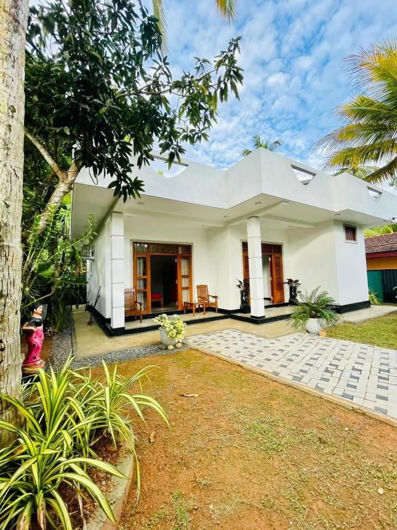 a white house with a tree in front of it at Bentota Upali Villa in Bentota