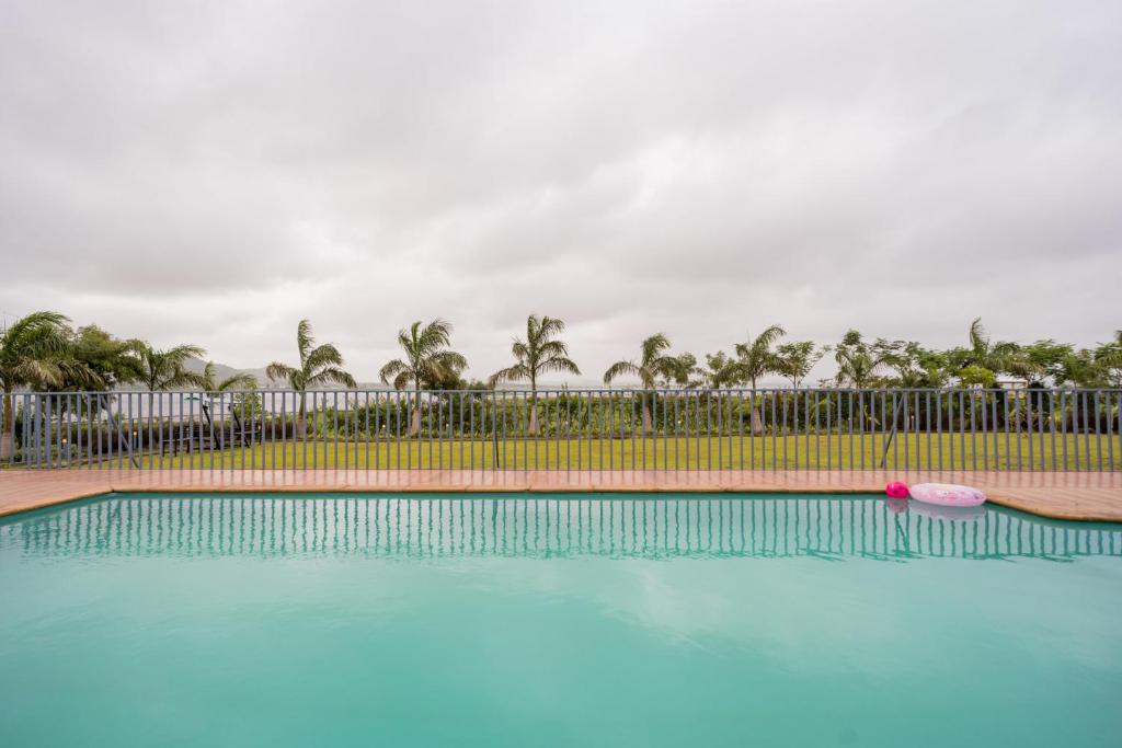 ナーシクにあるStayVista's Eva Villa - Lakeside Luxury with Modern Decor, Pool & Expansive Lawn - Near Sulaのフェンスの前にピンクのフリスビーがある大きなプール