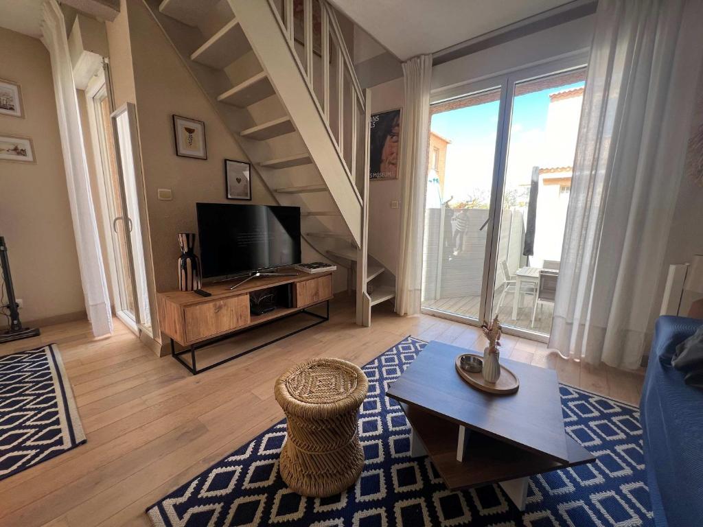 un salon avec un canapé et une télévision dans l'établissement Valras-Loc Le Bonheur a la Plage, à Valras-Plage