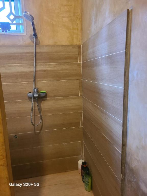 a shower in a bathroom with a wooden wall at White Jaguar House in Bwejuu