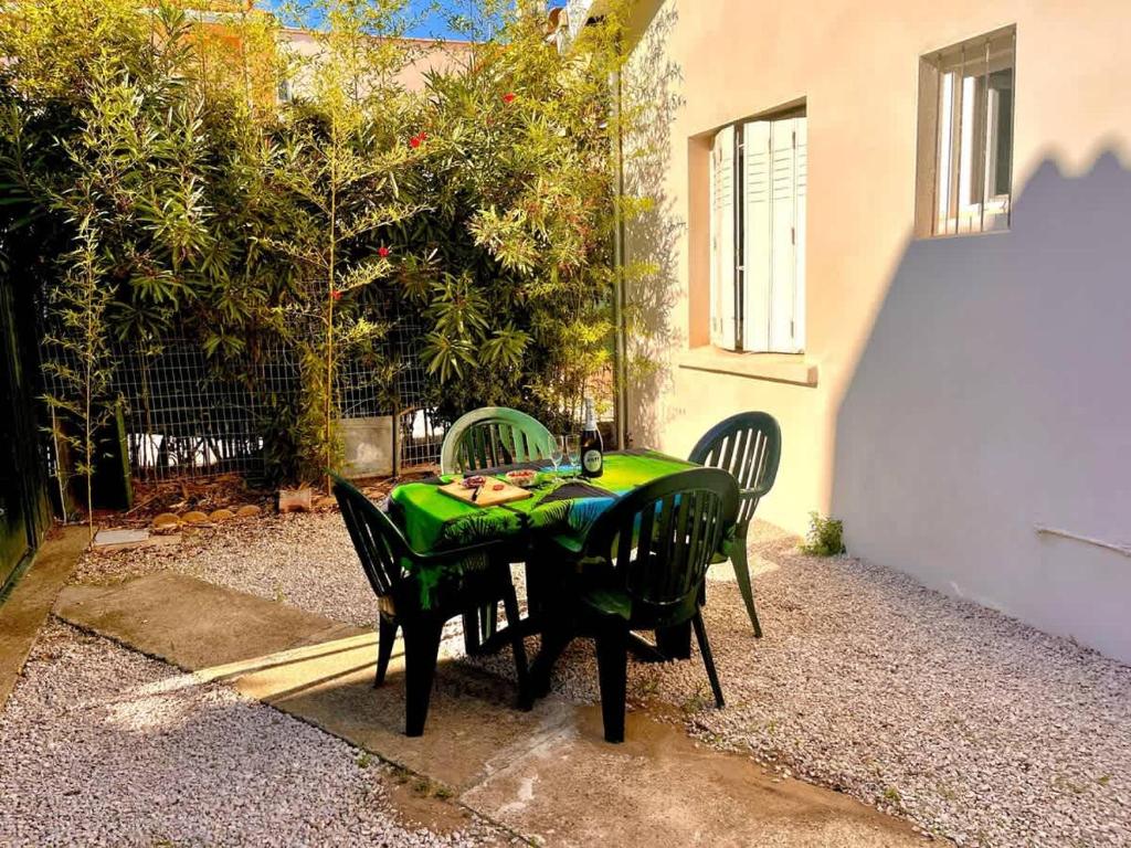 a green table with four chairs in a backyard at Maison Sympa in Valras-Plage