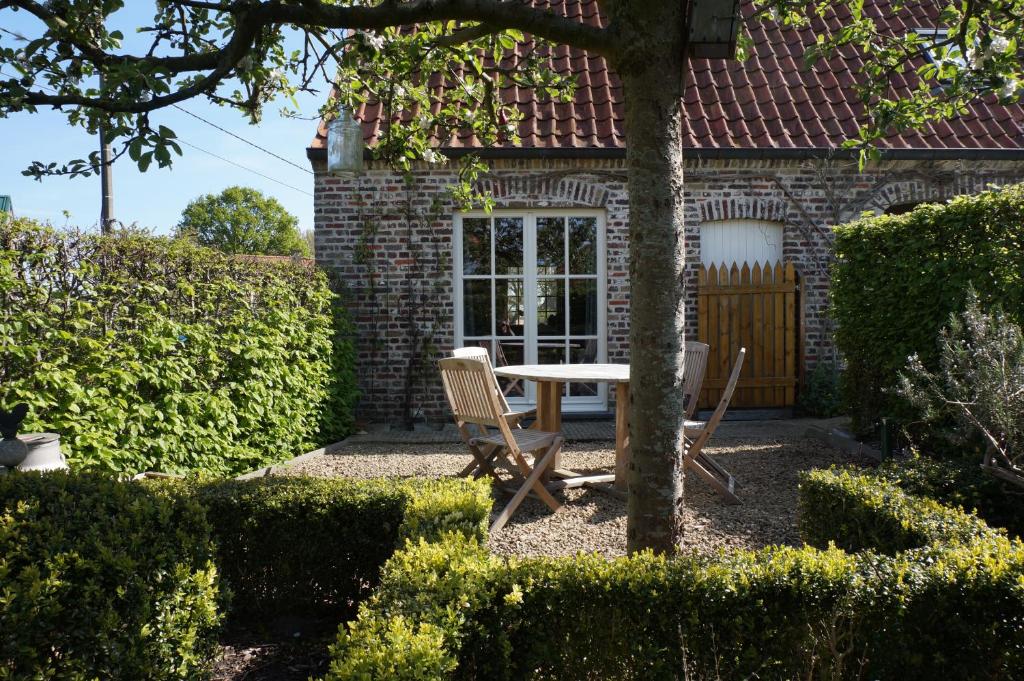 uma mesa e cadeiras em frente a uma casa em Jardin de Lieze em Maldegem