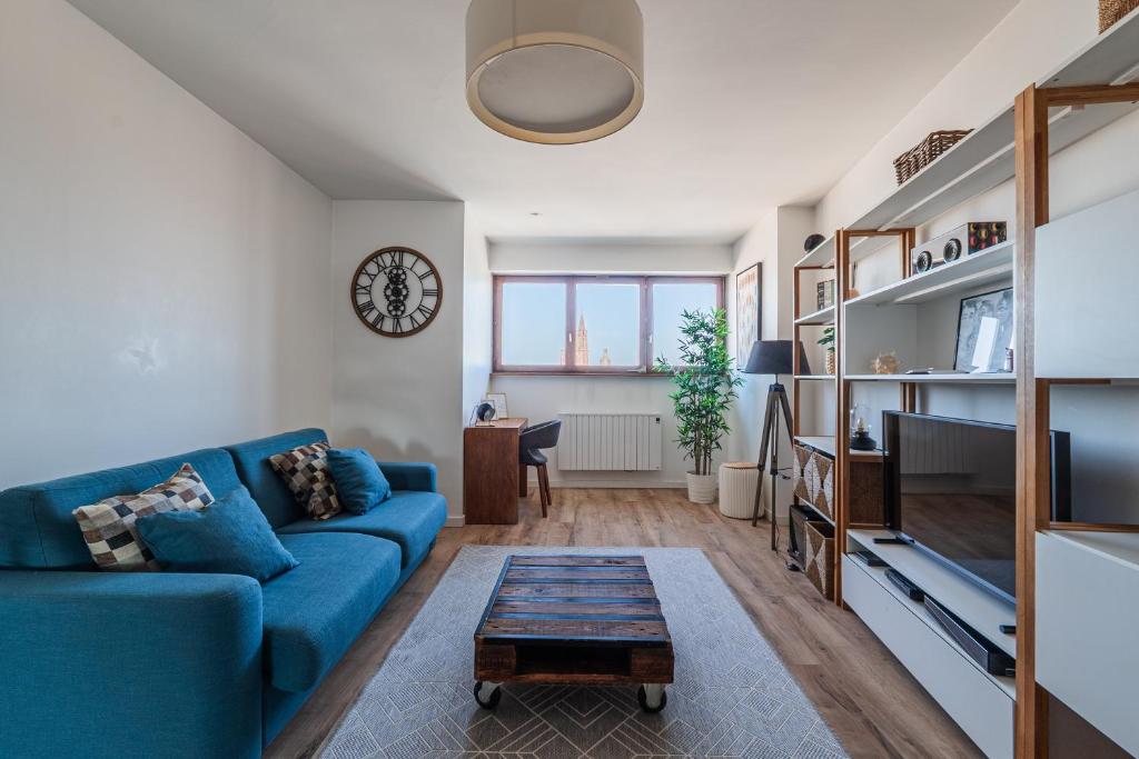 un salon avec un canapé bleu et une table dans l'établissement Panorama Cathédrale - Appt lumineux avec parking privé, à Strasbourg