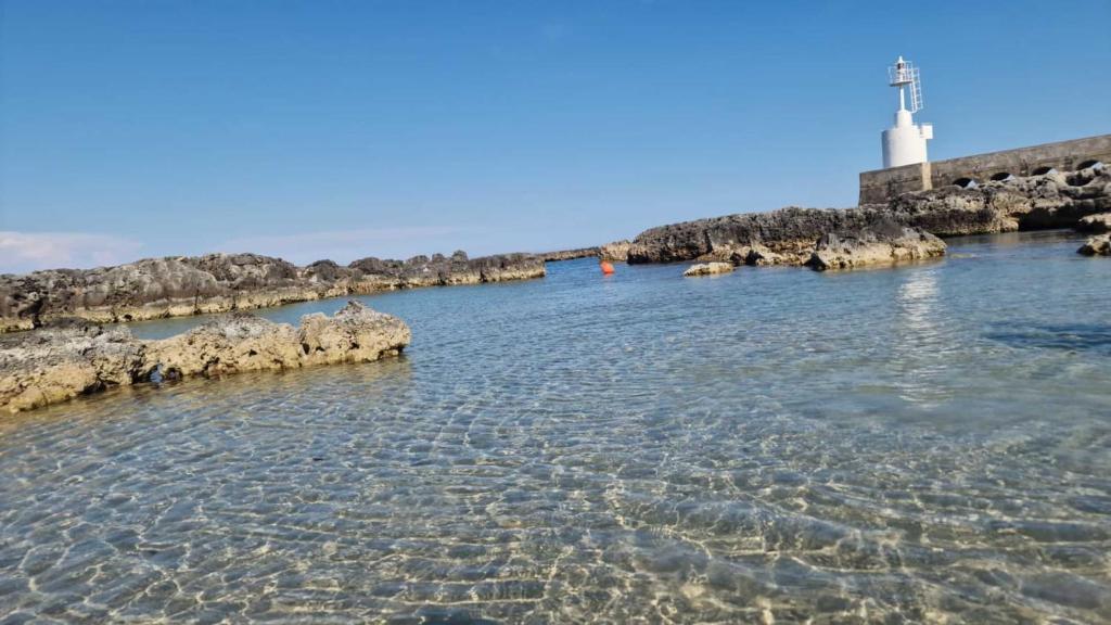 a body of water with a lighthouse in the background at Meraviglia d'Otranto in Otranto