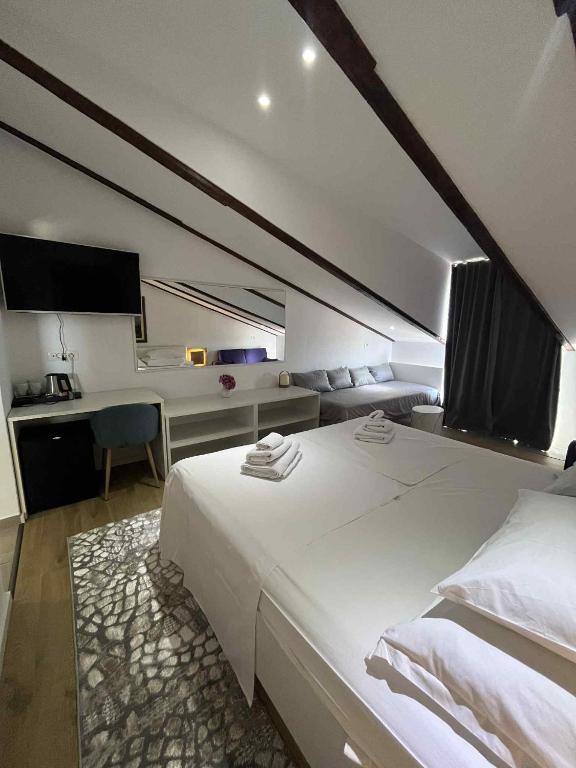 a bedroom with a large white bed and a desk at Dela in Hvar