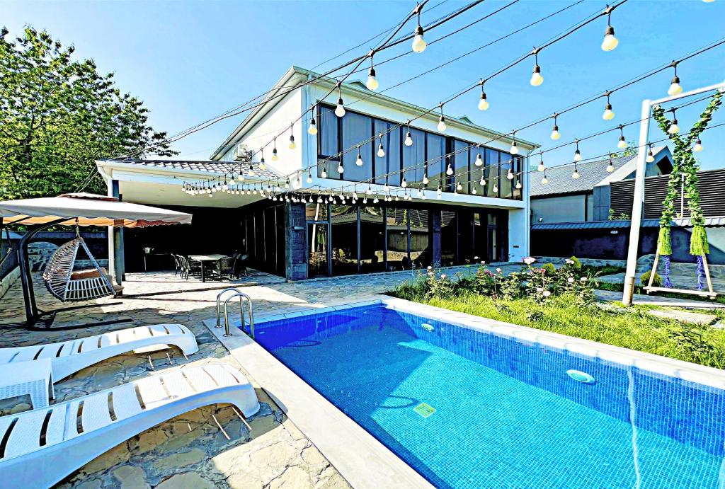 a house with a swimming pool in front of a house at Qafqaz Resort loft Style in Gabala