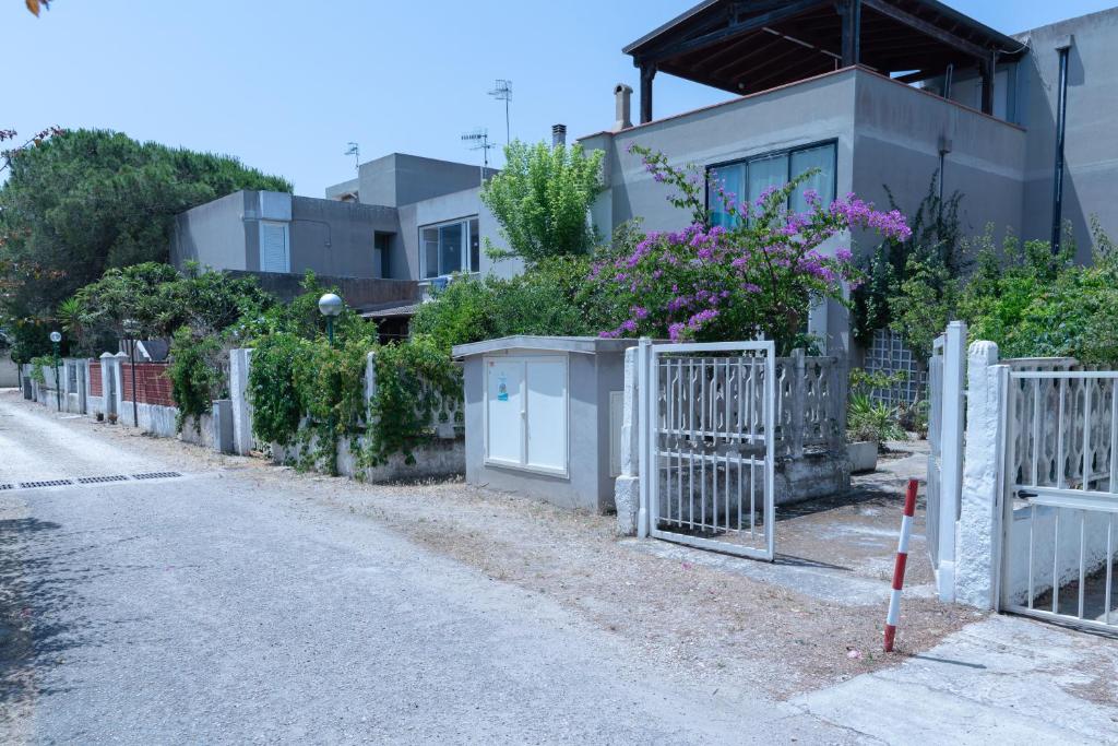 a fence in front of a house with flowers at La Casa della Riviera in Platamona