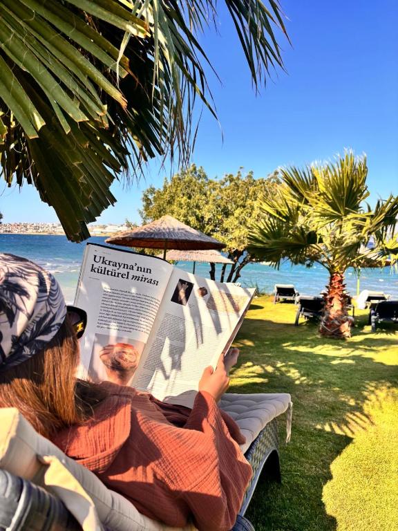 a woman sitting in a chair reading a newspaper at Sato Design Hotel in Çeşme
