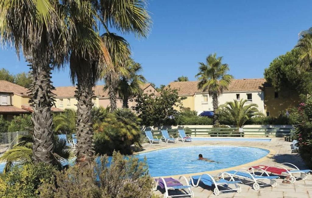 une personne se baignant dans une piscine bordée de palmiers dans l'établissement Havre de paix a Vendres-Plage, maison avec jardin et piscine, à Vendres