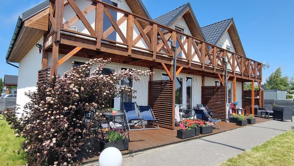 a house with a deck with chairs and flowers at Domki Białe Zacisze in Mielenko