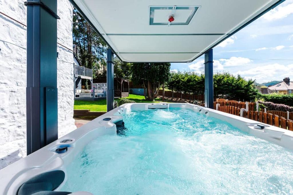a hot tub in a backyard with a basketball hoop at Mochdre Holiday Cottages in Mochdre