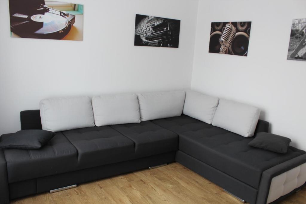 ein schwarzes Sofa in einem Zimmer mit Bildern an der Wand in der Unterkunft Apartment For Guests with Soul in Winnyzja