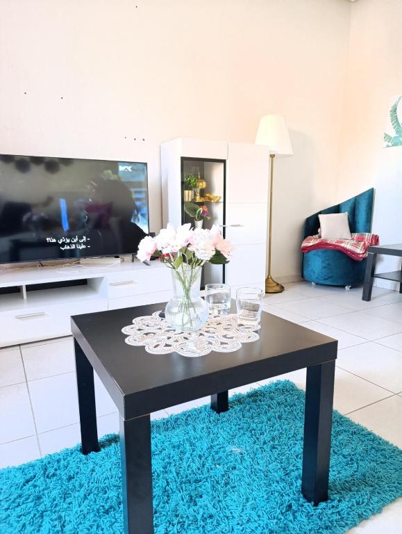 a living room with a table with a vase of flowers at Logement tout confort, équipé ! in Casablanca