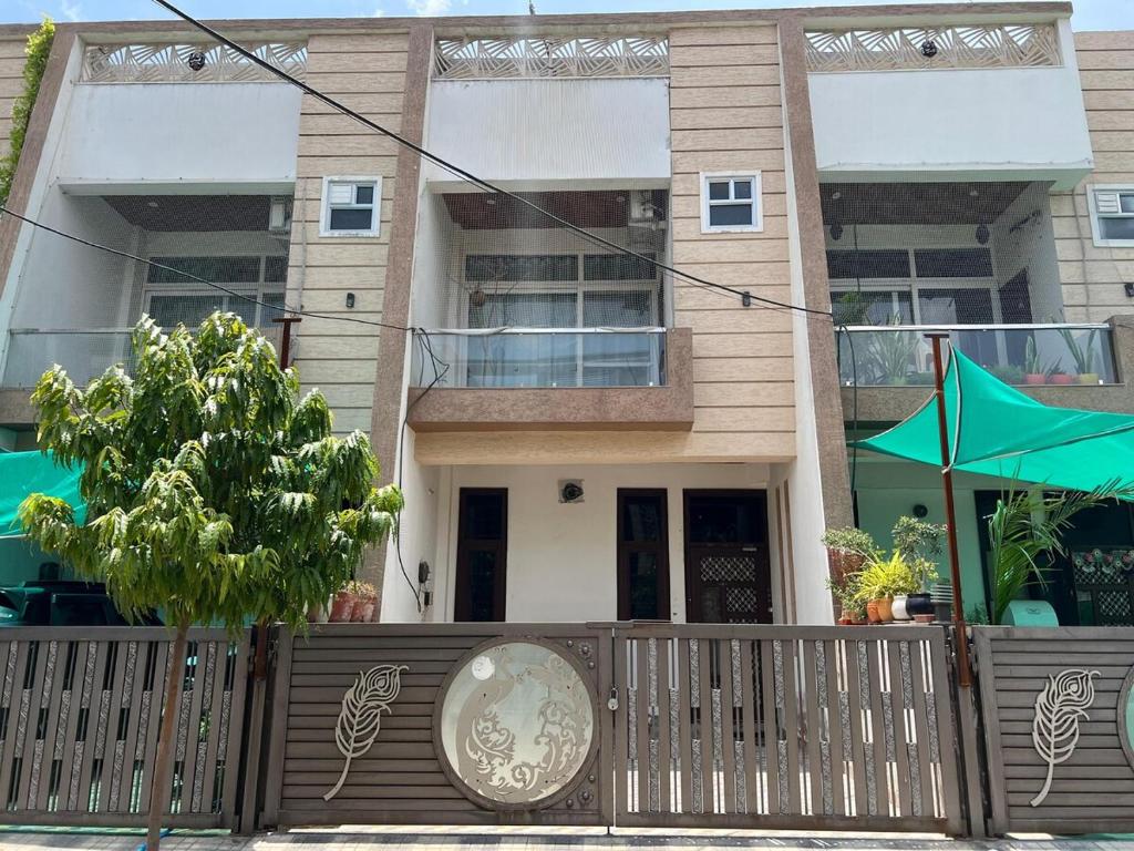 a house with a fence and an umbrella in front of it at The Roots of Jaipur Home stay in Jaipur