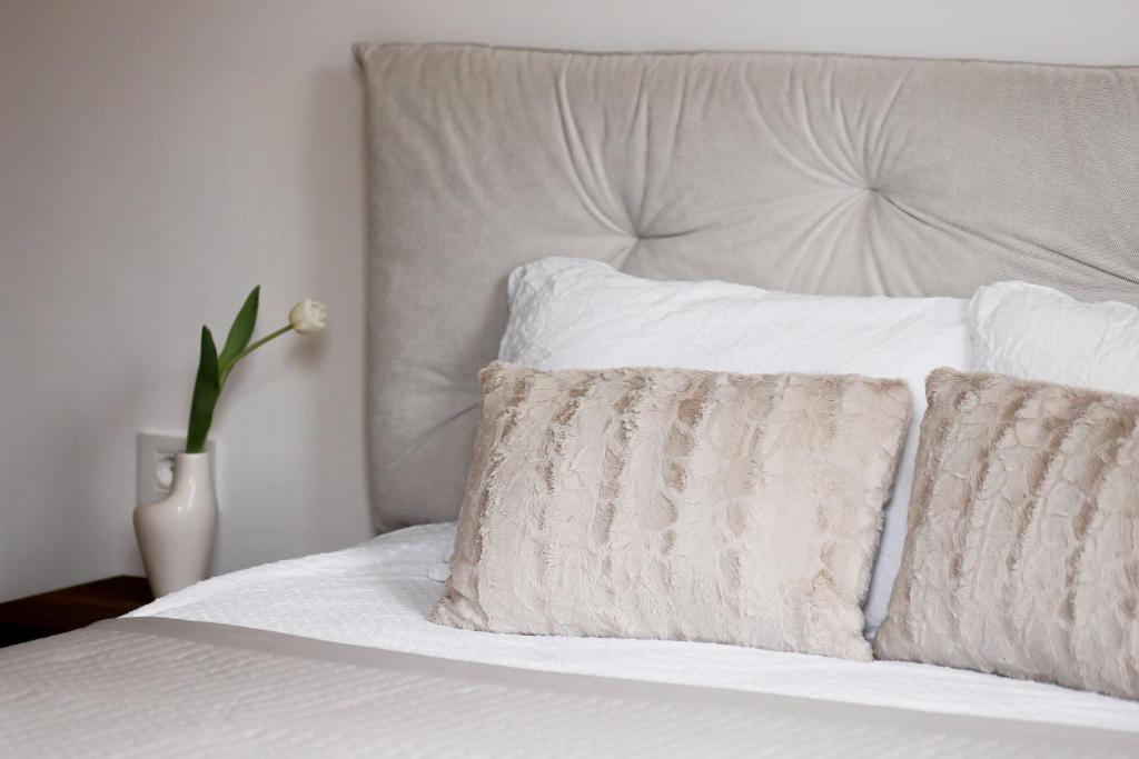 a white bed with a pillow and a vase with a flower at Valeri Lux Becici in Rafailovici