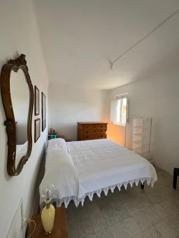 a bedroom with a white bed and a mirror at Panorama nel borgo in Monteciccardo