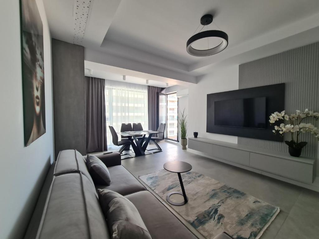 a living room with a couch and a tv at Residence Sole by Axxis Nova Resort - Apartament luxury 70mp cu terasa si vedere la mare, acces direct pe plaja Axxis Beach BluFlag - Mamaia Nord - Parcare gratuita in Mamaia