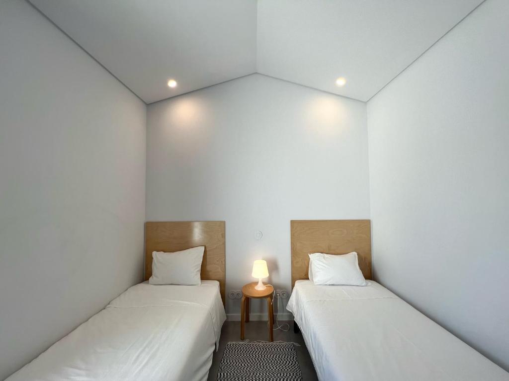 two beds in a room with a lamp between them at Casa do Meio #5 in São Martinho do Porto