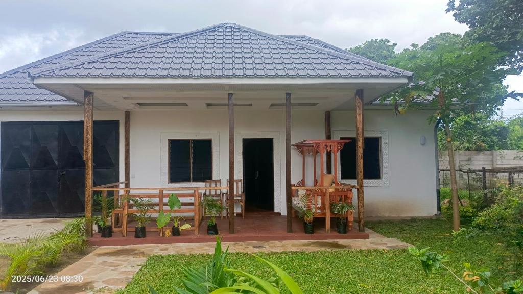 ein kleines weißes Haus mit einer Veranda in der Unterkunft Shalom Wellspring Cottage in Malindi