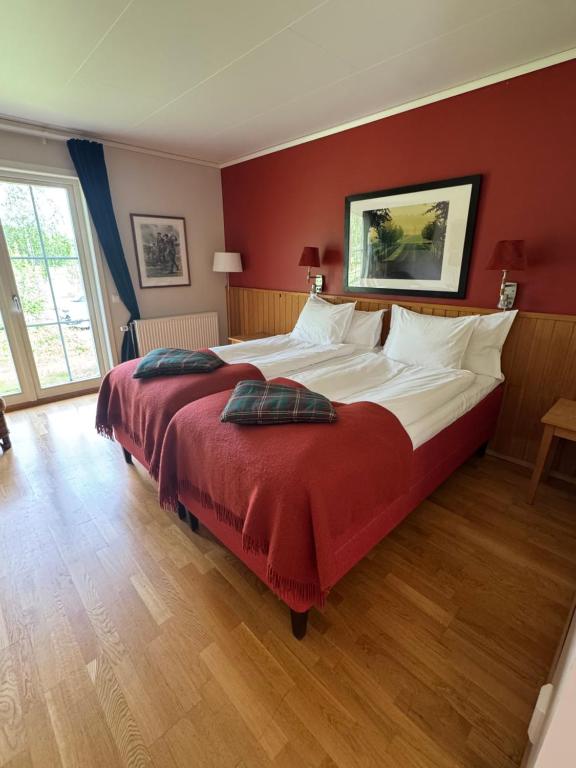 a bedroom with a large bed with a red wall at Trosa Åda Krog Hotell & Konferens in Trosa