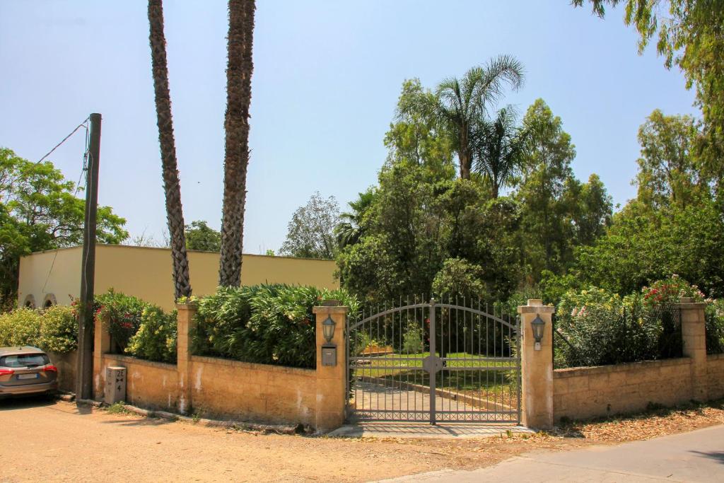 a gate in a park with palm trees and a car at Villa Vittoria in Fontanelle