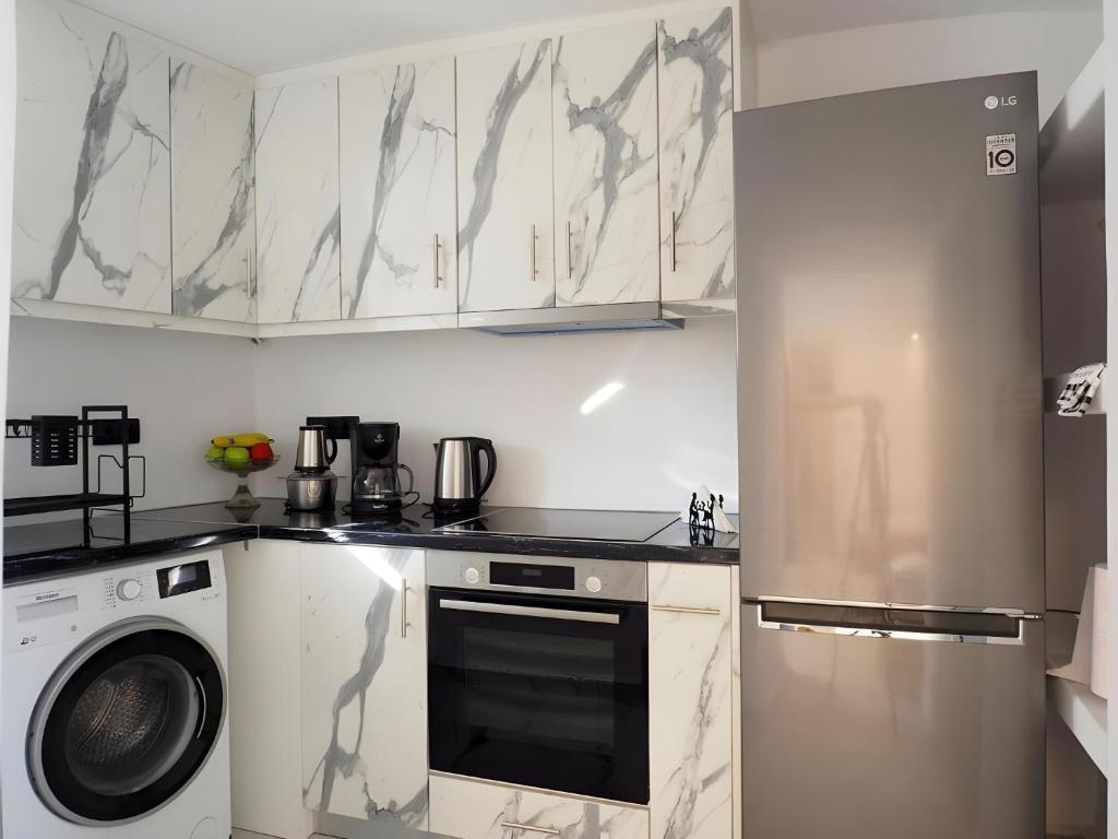 a kitchen with white cabinets and a washer and dryer at Mitropolis Apartment in Naxos Chora
