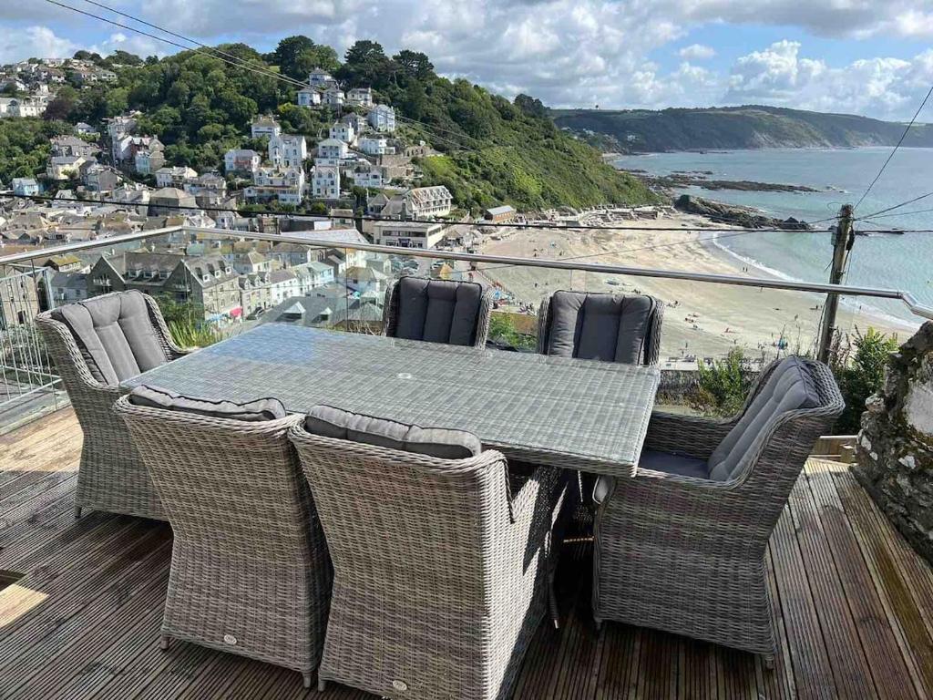 a table and chairs on a deck with a view of a beach at Cornwall Large Beach House Sea & Beach Views - 4 Bedrooms & 3 Bathrooms in Looe