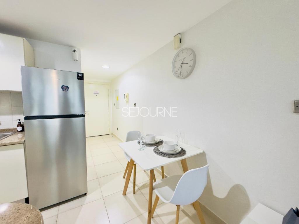a kitchen with a stainless steel refrigerator and a table at DA86 - Well Design Studio in Dubai Arch tower in Dubai